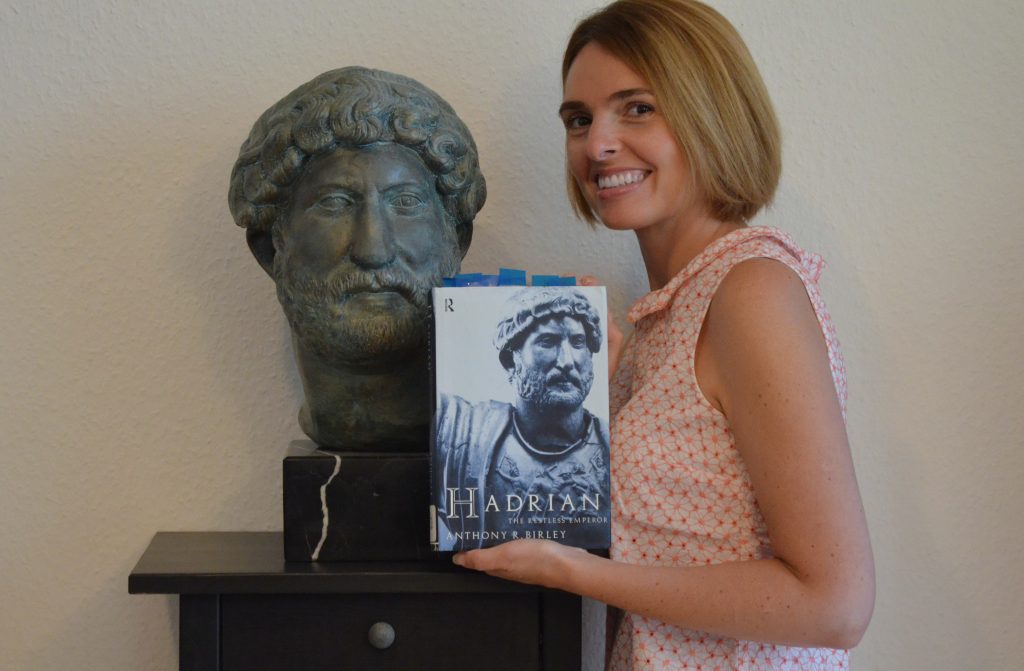 Carole Raddato con un busto del emperador Adriano y su libro base