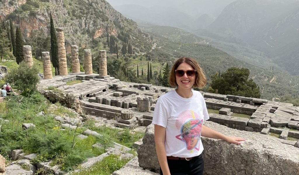 Carole Raddato en Delfos ante el templo de Apolo