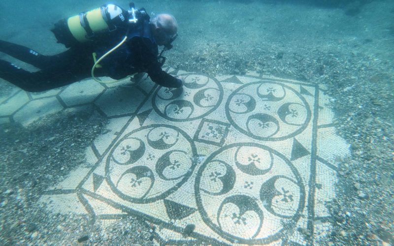 Submarinista enseñando un mosaico romano en la Villa Protiro en la ciudad romana sumergida de Baiae